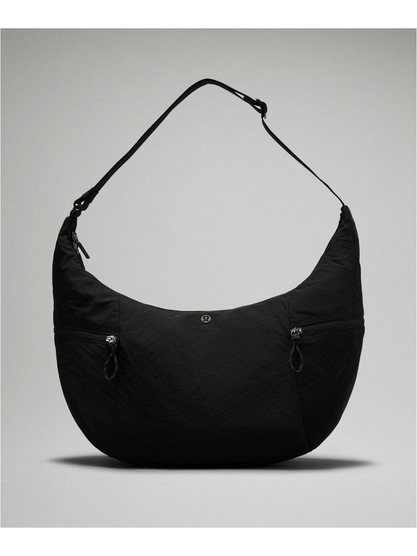 کیف اسلوچی اسلینگ 13 لیتری Lululemon، کیف اسلینگ مشکی از روبه‌رو با جیب‌های بیرونی و بند بلند روی پس‌زمینه روشن