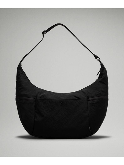 کیف اسلوچی اسلینگ 13 لیتری Lululemon، کیف اسلینگ مشکی با فرم هلالی و بند بلند از پشت روی پس‌زمینه روشن