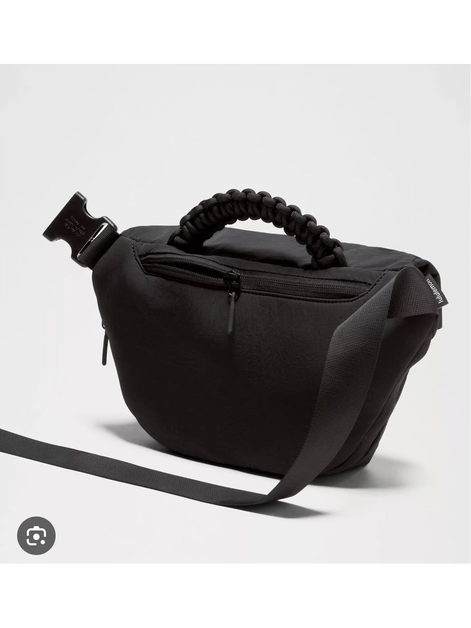 بلت بگ 3 لیتری Lululemon، پشت کیف کمری مشکی با جیب زیپ‌دار، دسته بافته‌شده و بند بلند روی پس‌زمینه روشن