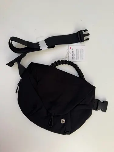 بلت بگ 3 لیتری Lululemon، کیف کمری مشکی با دسته بافته‌شده و بند سگک‌دار جداشده روی سطح روشن