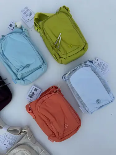 باتل بگ اورجینال Lululemon، کیف‌های بنددار آبی، سبز لیمویی، نارنجی، زرشکی و کرم روی زمینه روشن