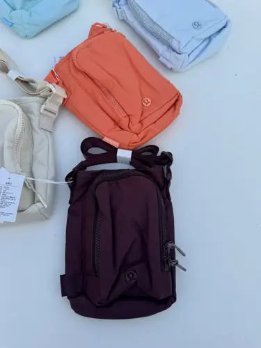 باتل بگ اورجینال Lululemon، دو کیف بنددار نارنجی و زرشکی با جیب جلو، روی زمینه روشن