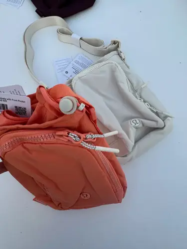 باتل بگ اورجینال Lululemon، کیف‌های کرم و نارنجی با بند پهن، روی زمینه روشن