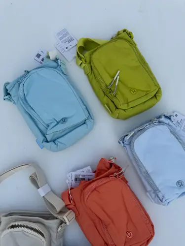 باتل بگ اورجینال Lululemon، کیف‌های بنددار زرشکی، آبی، سبز لیمویی، نارنجی و کرم روی زمینه روشن