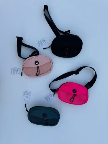 بلت بگ کرو Lululemon، کیف‌های بیضی مشکی، صورتی و آبی تیره با بند و سگک پهن، روی زمینه روشن - تصویر اصلی