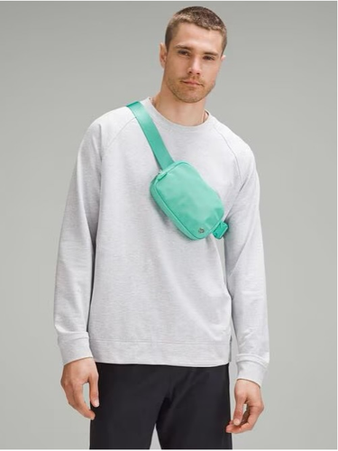 بلت بگ Lululemon، فیروزه‌ای؛ مورب روی سینه مدل مرد با بلوز سفید، روی زمینه خاکستری