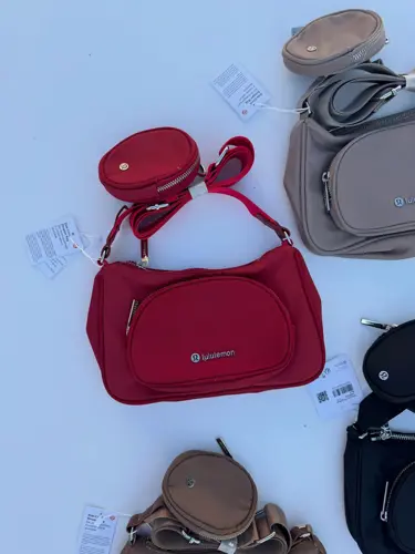 کراس بادی نانو پوچ 2 لیتری Lululemon، کیف‌های مشکی، قرمز، خاکستری و قهوه‌ای با کیفک گرد متصل به بند، روی زمینه روشن