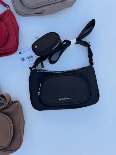 کراس بادی نانو پوچ 2 لیتری Lululemon، کیف‌های مشکی، قرمز، خاکستری و قهوه‌ای با کیفک گرد متصل به بند، روی زمینه روشن