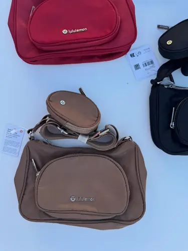 کراس بادی نانو پوچ 2 لیتری Lululemon، کیف‌های مشکی، قرمز، خاکستری و قهوه‌ای با کیفک گرد متصل به بند، روی زمینه روشن