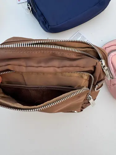 کیف ساید سینچ Lululemon، نمای نزدیک جیب زیپ‌دار داخل کیف قهوه‌ای با دهانه باز