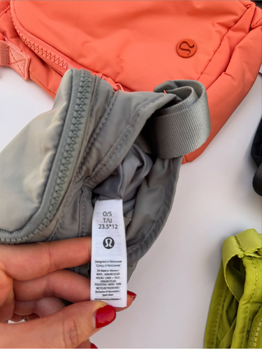 باتل بگ اورجینال Lululemon، خاکستری؛ نمای نزدیک برچسب سفید داخلی و بند کنار کیف در دست