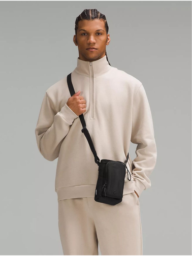 باتل بگ اورجینال Lululemon، مشکی؛ کیف کوچک بنددار روی شانه مدل مرد با لباس کرم، روی زمینه خاکستری