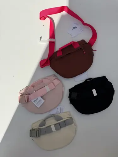 بلت بگ 3 لیتری Lululemon، کیف‌های زرشکی، صورتی، مشکی و بژ با درپوش منحنی و بند پهن، روی زمینه روشن