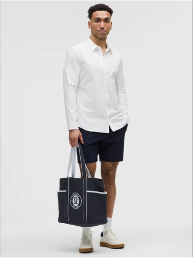 توت بگ کتان Lululemon، مشکی با نشان گرد سفید؛ در دست مدل مرد با پیراهن سفید و شلوارک تیره