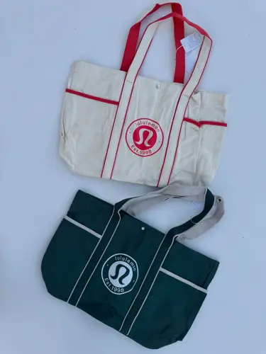 توت بگ کتان Lululemon، دو توت‌بگ سفید با خطوط قرمز و سبز با خطوط سفید و لوگوی گرد لولولمون - تصویر اصلی