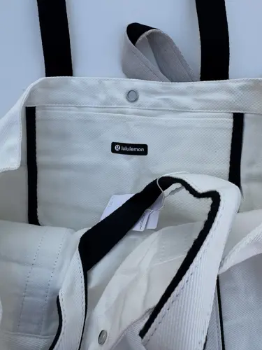 توت بگ کتان Lululemon، سفید؛ نمای نزدیک دسته‌ها، دکمه و نشان کوچک lululemon