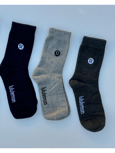 جوراب ساقدار Lululemon، جوراب‌های مشکی، سفید و خاکستری با نشان لولولمون روی ساق و نوشته روی کف پا، روی زمینه روشن