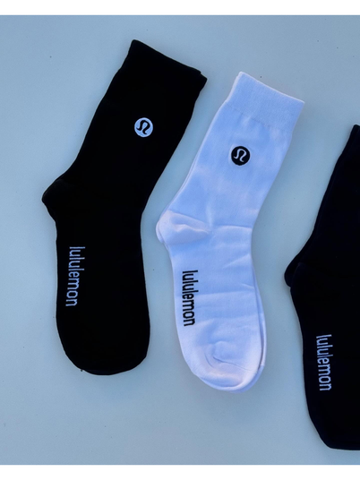 جوراب ساقدار Lululemon، جوراب‌های مشکی، سفید و خاکستری با نشان لولولمون روی ساق و نوشته روی کف پا، روی زمینه روشن