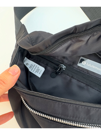 کراس بادی نورلاست Lululemon، مشکی؛ نمای نزدیک جیب زیپ‌دار و برچسب داخلی در دست