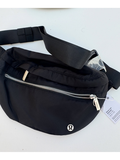 کراس بادی نورلاست Lululemon، مشکی؛ کیف باز با زیپ نقره‌ای جلو و محفظه اصلی، روی زمینه روشن