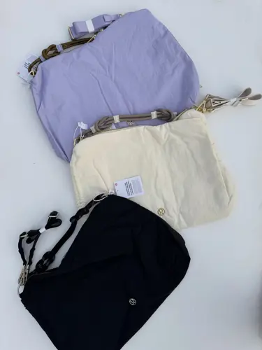 کراس بادی کانورتیبل Lululemon، کیف‌های بنفش روشن، کرم و مشکی با بندهای کوتاه و یراق طلایی روی سطح سفید - تصویر اصلی