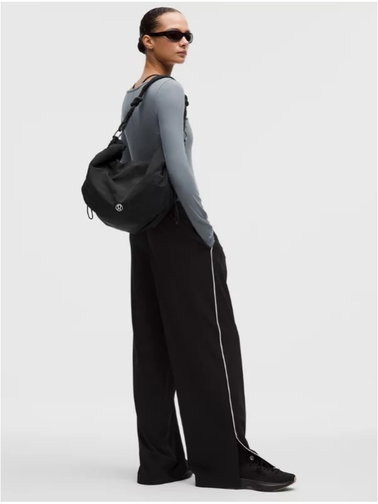 کراس بادی کانورتیبل Lululemon، کیف مشکی روی پشت مدل با بلوز خاکستری، شلوار مشکی و عینک آفتابی
