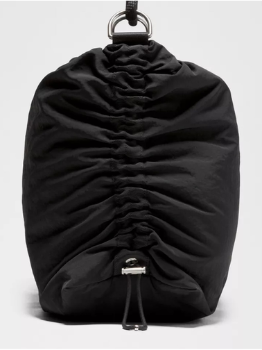 کراس بادی کانورتیبل Lululemon، پشت کیف مشکی با پارچه جمع‌شده و بند جمع‌کننده، آویزان از حلقه روی پس‌زمینه روشن