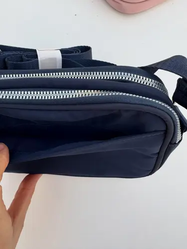 کراس بادی کمرا بگ 2 لیتری Lululemon، سرمه‌ای؛ نمای نزدیک محفظه‌های زیپ‌دار باز کیف در دست