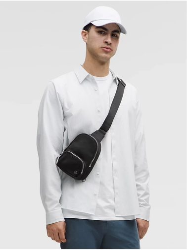 کیف اسمال اسلینگ Lululemon، مشکی؛ روی شانه مدل مرد با کلاه و تیشرت سفید