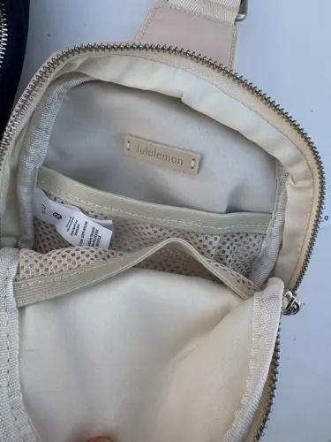 کیف اسمال اسلینگ Lululemon، کرم؛ نمای داخل کیف باز با جیب توری و برچسب
