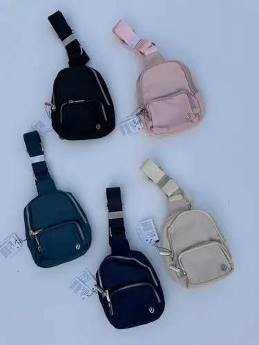 کیف اسمال اسلینگ Lululemon، کیف‌های تک‌بند مشکی، سرمه‌ای، آبی تیره، صورتی و کرم با جیب زیپ‌دار، روی زمینه روشن - تصویر اصلی