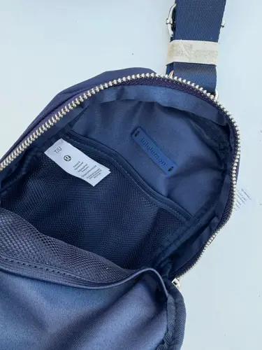 کیف اسمال اسلینگ Lululemon، سرمه‌ای؛ نمای داخل کیف باز با برچسب و جیب آستر