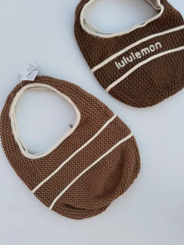 کیف بافت Lululemon، کیف‌های بافتنی قهوه‌ای با نوار و نوشته سفید lululemon، روی زمینه روشن