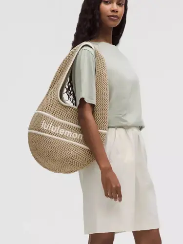 کیف بافت Lululemon، بژ با نوار سفید؛ روی شانه مدل با لباس روشن - تصویر دوم