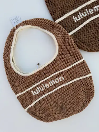 کیف بافت Lululemon، کیف‌های بافتنی قهوه‌ای با نوار و نوشته سفید lululemon، روی زمینه روشن