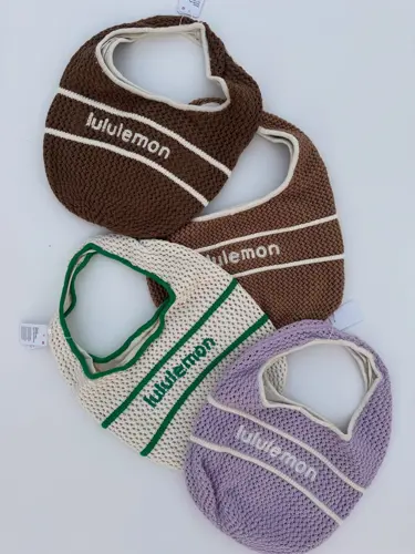 کیف بافت Lululemon، چیدمان کیف‌های بافتنی قهوه‌ای، یاسی و کرم با نوارهای متضاد و نوشته lululemon - تصویر اصلی
