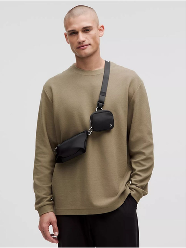 کیف دوتکه Lululemon، مشکی؛ دو کیف کوچک روی بند مورب سینه مدل مرد با بلوز زیتونی