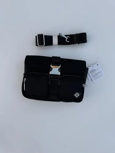کیف دوشی مولتی پاکت Lululemon، مشکی با سگک وسط و دو جیب جلو؛ کنار بند جداشونده
