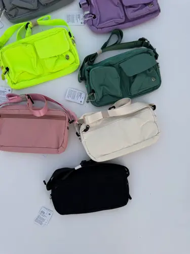 کراس بادی مولتی پاکت Lululemon، چیدمان کیف‌های چندجیب رنگارنگ سبز، بنفش، صورتی، کرم و مشکی روی زمینه روشن - تصویر دوم