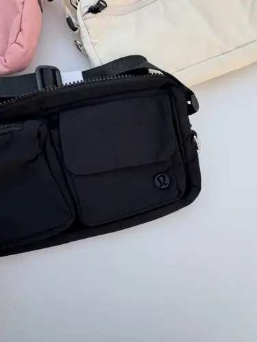 کراس بادی مولتی پاکت Lululemon، مشکی با دو جیب جلو و نشان لولولمون؛ روی زمینه روشن