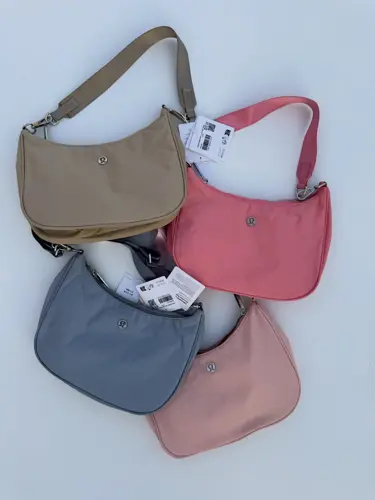 کیف شولدر Lululemon، کیف‌های شانه‌ای بژ، صورتی، آبی خاکستری و صورتی چرک با بند کوتاه، روی زمینه روشن