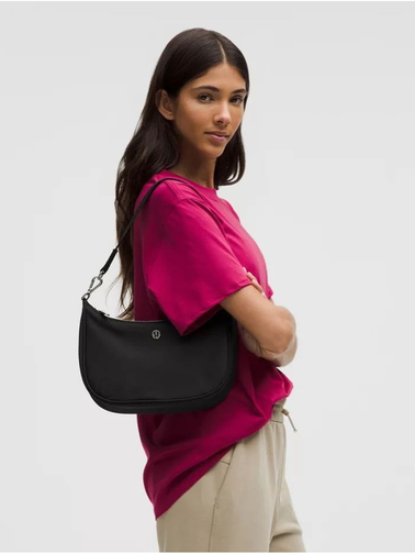 کیف شولدر Lululemon، مشکی؛ روی شانه مدل با تیشرت صورتی و شلوار بژ