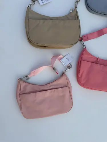 کیف شولدر Lululemon، کیف‌های شانه‌ای بژ، صورتی، آبی خاکستری و صورتی چرک با بند کوتاه، روی زمینه روشن