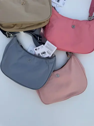 کیف شولدر Lululemon، کیف‌های شانه‌ای بژ، صورتی، آبی خاکستری و صورتی چرک با بند کوتاه، روی زمینه روشن