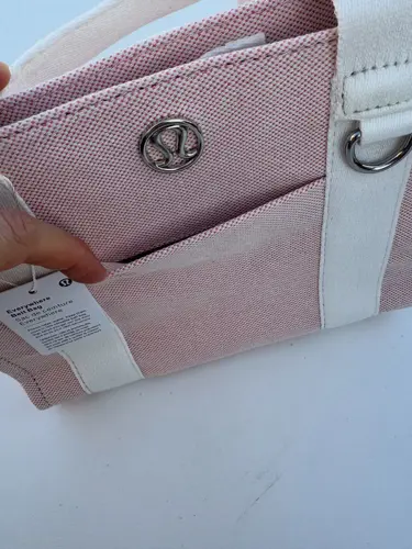 کیف کانواس Lululemon، صورتی روشن؛ نمای نزدیک جیب جلو، بافت پارچه و نشان فلزی لولولمون - تصویر دوم