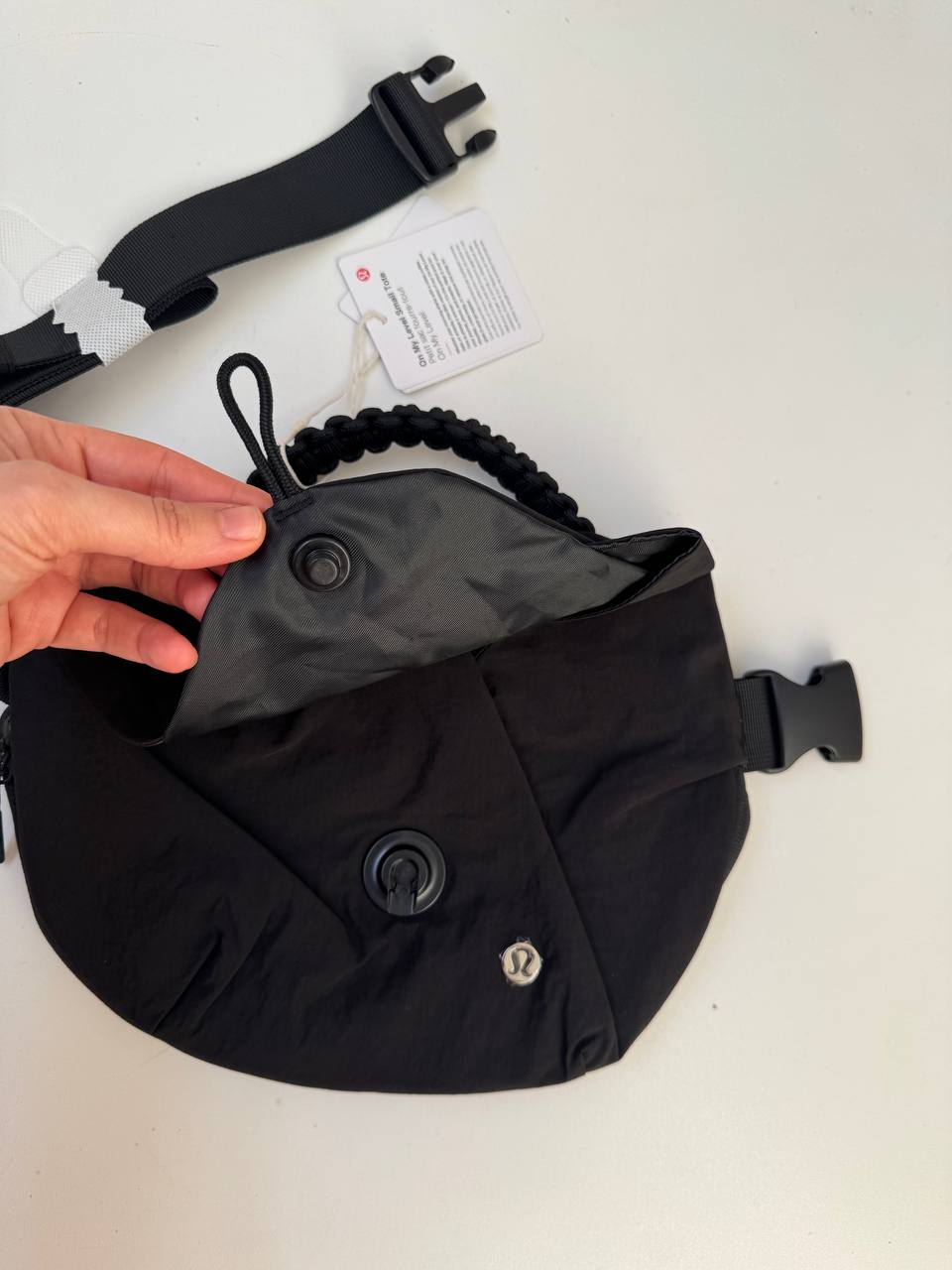 بلت بگ 3 لیتری Lululemon، کیف کمری مشکی با درپوش باز و دو دکمه گرد، در دست