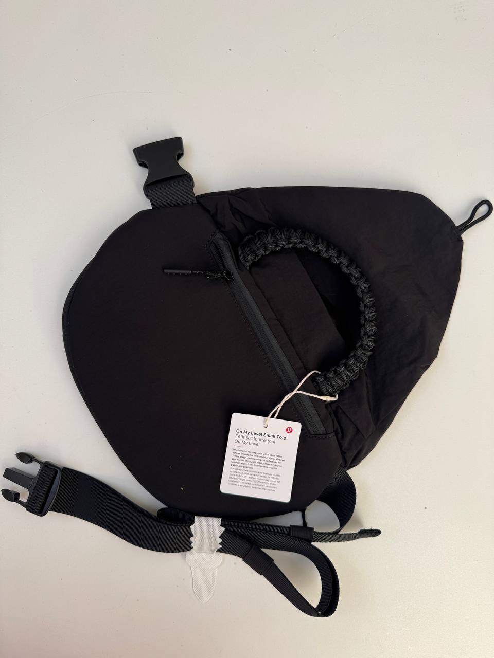 بلت بگ 3 لیتری Lululemon، پشت کیف کمری مشکی با دسته بافته‌شده، زیپ و بند سگک‌دار روی سطح روشن