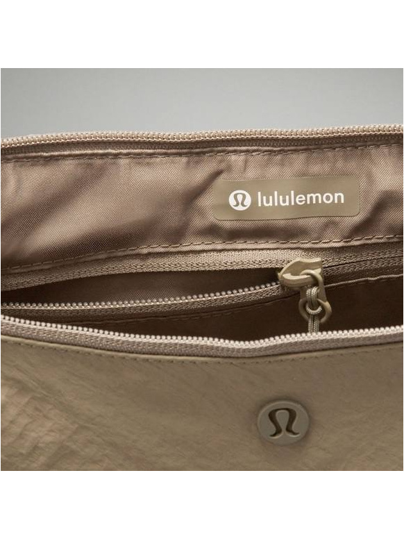 کیف اسلوچی اسلینگ 13 لیتری Lululemon، نمای نزدیک جیب زیپ‌دار و نوشته lululemon داخل کیف زیتونی