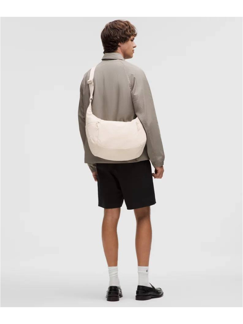 کیف اسلوچی اسلینگ 13 لیتری Lululemon، کیف اسلینگ کرم به‌صورت مورب روی پشت مدل با بلوز خاکستری و شلوارک مشکی