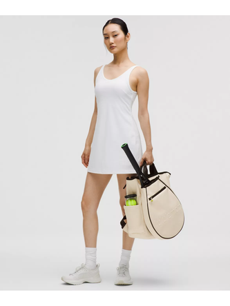 کیف تنیسی راکت بگ Lululemon، کیف تنیس کرم همراه کاور و دسته راکت در دست مدل با لباس کوتاه سفید